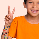 Child wearing colorful temporary tattoos on an orange background