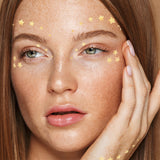 A female with gold metallic temporary tattoos stars around her eyes